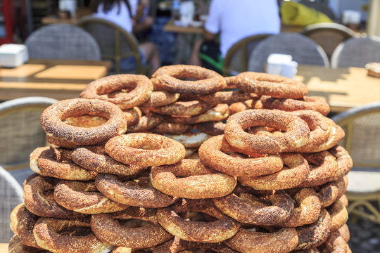Pile of simits (turkish bagels) on street during daytime.
