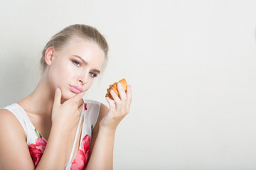 Disgruntled dieting blonde woman holding delicious dessert with cream. Space for text