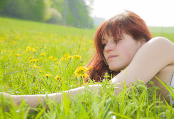 Beautiful smiling woman lying on a grass outdoor.