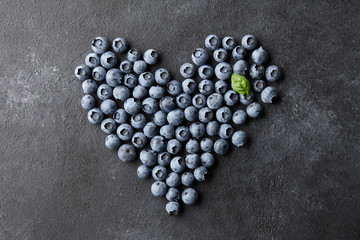 Fresh blueberries heart shape on black background. Healthy food eating concept.