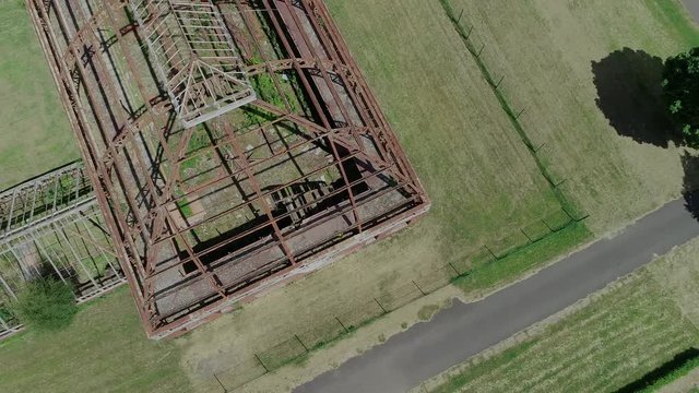 Aerial footage of the metal skeleton of a large abandoned glasshouse.