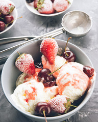 Vanilla ice cream in a grey bowl. Homemade organic dessert with jam, sweet cherry and strawberry. Top view