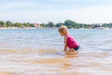 Fototapeta na wymiar Little child girl on beach. Sea in background.