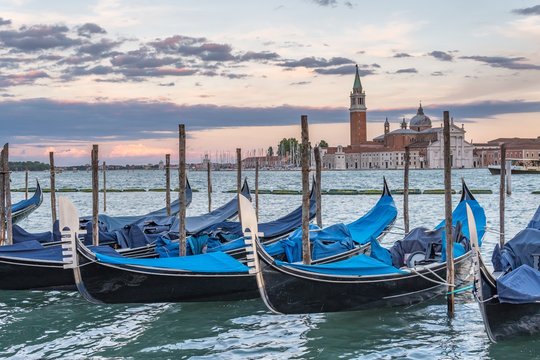 Many gondolas in Venice in Italy at sunset.