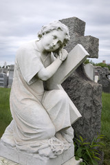 Trauernde Frau mit Kreuz am Friedhof