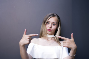 Portrait of blonde girl pointing on herself