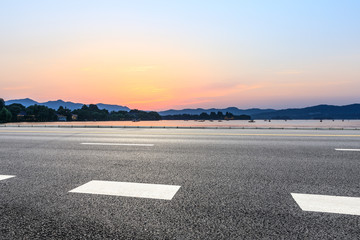 Fototapeta premium Empty asphalt road and hills silhouette at sunset