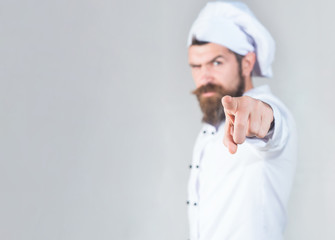 Chef man. Confident male chef with beard, mustache shows finger on you. Cook points forward. Chef in uniform pointing at you. Chef, cook, baker pointing to front. Selective focus on hand. Copy space.