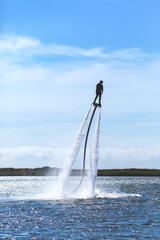 a man is riding a flyboard on a lake on a sunny day, toned