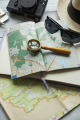 Travel planning concept, notebook, map, documents, hat, camera, accessories for trip, outfit of traveller, tourist making his notes, selective focus