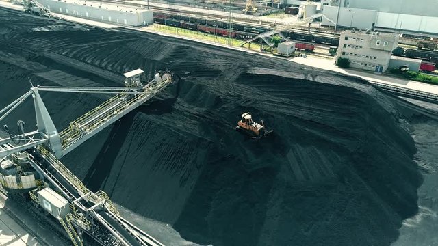Aerial view of moving bulldozer on the top of coal pile of a power plant