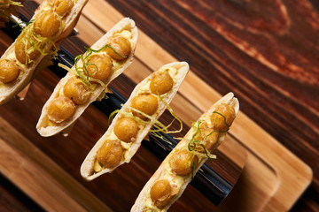 Delicious Labne and karri snack food with fried yellow peas, curry, lemon peel, in bread cake pita. vegetarian food on silver stand at luxury restaurant table, top view