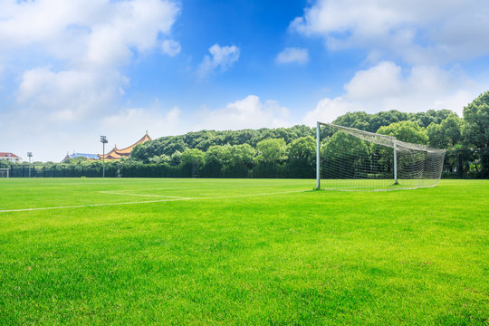 Green football field under blue sky background