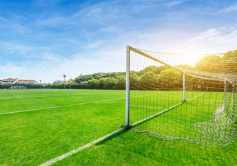 Fototapeta premium Green football field under blue sky background