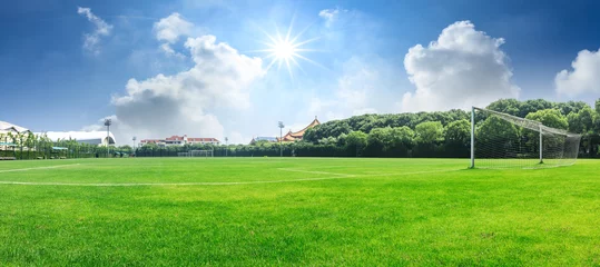Fotobehang Groen voetbalveld onder blauwe hemelachtergrond © ABCDstock