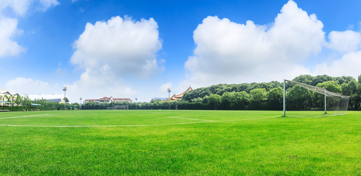 Green football field under blue sky background
