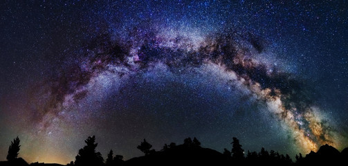 Panoramic astrophotography of whole visible Milky Way galaxy. Silhouette of mountains. Stars, nebula and stardust at night sky landscape - obrazy, fototapety, plakaty