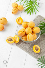 Fresh apricots in a round glass pial on a white board table..