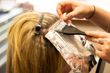 Blonde woman receiving haircut at a salon. Woman with blonde highlights. Hair foils on a female client. Master stylist cutting hair