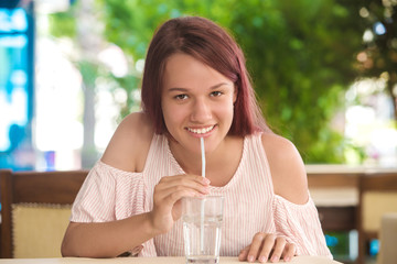 Young pretty girl drinking water from a glass