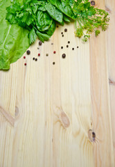 Basil and salad and dill next to pepper peas on wooden background