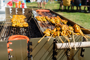 Fleischbestückte Holzspieße und Wurst auf einem Kohlegrill im Sommer