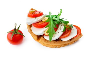 Belgium waffle with mozarella, tomatoes, olives and arugula isolated on white background