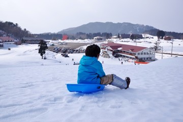 Fototapeta na wymiar スキーリゾートでソリ遊びをする子供