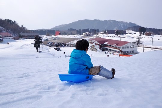 スキーリゾートでソリ遊びをする子供