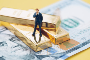Wealth management concept, miniature people business man standing on gold bullion ingot stack on US...