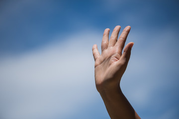 Fototapeta na wymiar Woman raise hand up showing the five fingers on blue sky with white cloud background