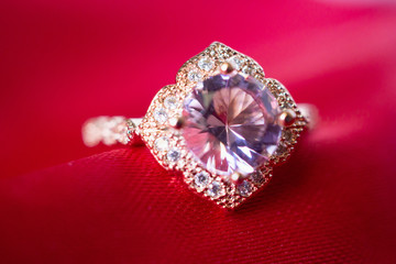 Jewelry luxury pink gold ring with sapphire gemstone on red fabric texture background