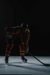 Fototapeta premium full length view of sportsman in protective sportswear playing ice hockey on black