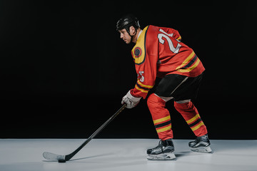 side view of professional young ice hockey player playing hockey and looking away on black © LIGHTFIELD STUDIOS