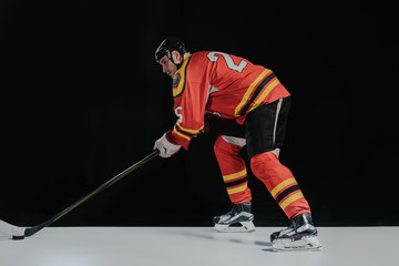 side view of professional sportsman playing hockey on black