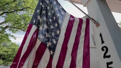 American Flag on a front porch on a breezy day. Perfect wind coming through with sun light leaks.