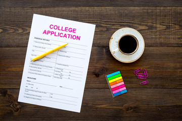 Apply college. Empty college application form near coffee cup and stationery on dark wooden...