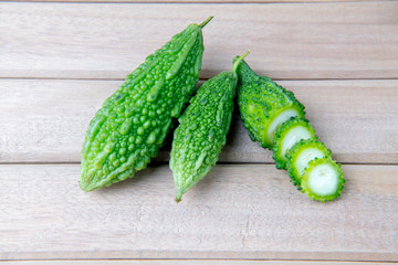 Closeup view of bitter gourd over wooden board background.