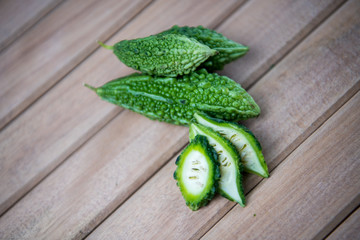 Closeup view of bitter gourd over wooden board background.
