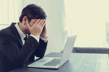 Tired frustrated business people feeling stressed, upset executives sitting near laptop, holding head in hands, worried about business problem failure, depressed by bad news,