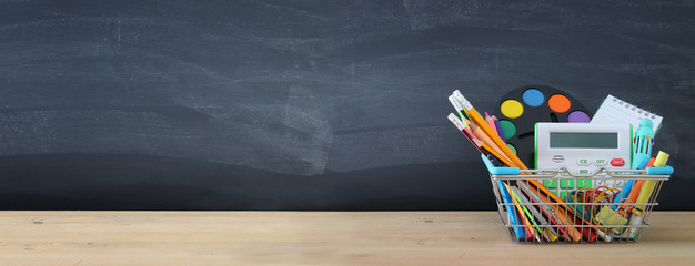 Banner of Shopping cart with school supply in front of blackboard. Back to school concept. © tomertu