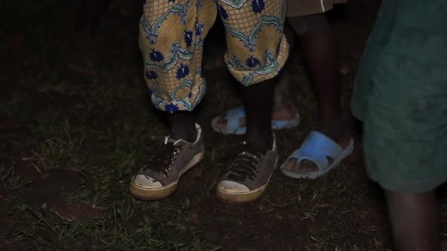 The feet of young boys / children in Uganda dance at night at a Wedding