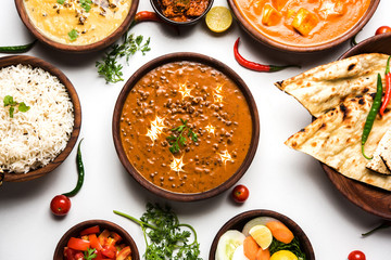 Assorted indian food for lunch or dinner, rice, lentils, paneer, dal makhani, naan, chutney, spices over moody background. selective focus   © StockImageFactory