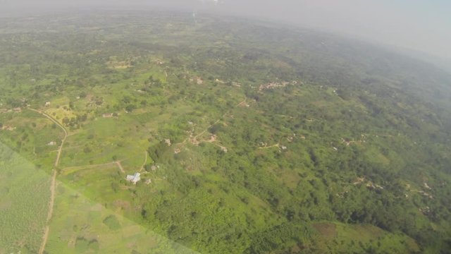 Looking out the window of a prop plane flying over Ugandan countryside