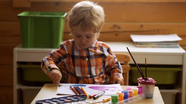 Concept of early childhood education, painting, talent, happy family and parenting. Cute, serious and focused boy drawing