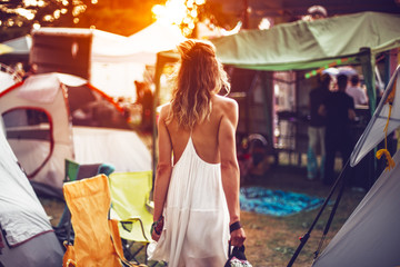 Beautiful young woman walking on festival camping tents for sunset dancig party - obrazy, fototapety, plakaty