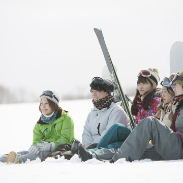 雪原に座り談笑をする若者たち