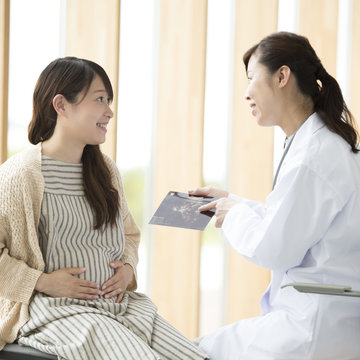 エコー写真を持ち話をする女医と妊婦