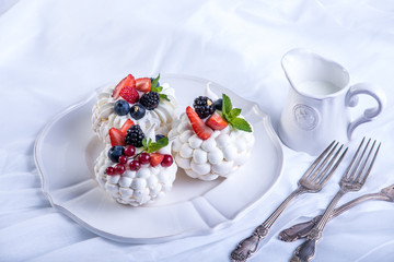 Delicate white meringues with fresh berries on the plate. Dessert Pavlova. Wedding cake.