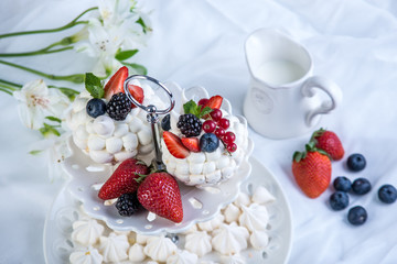 Delicate white meringues with fresh berries on the plate on white background. Dessert Pavlova. Wedding cake.